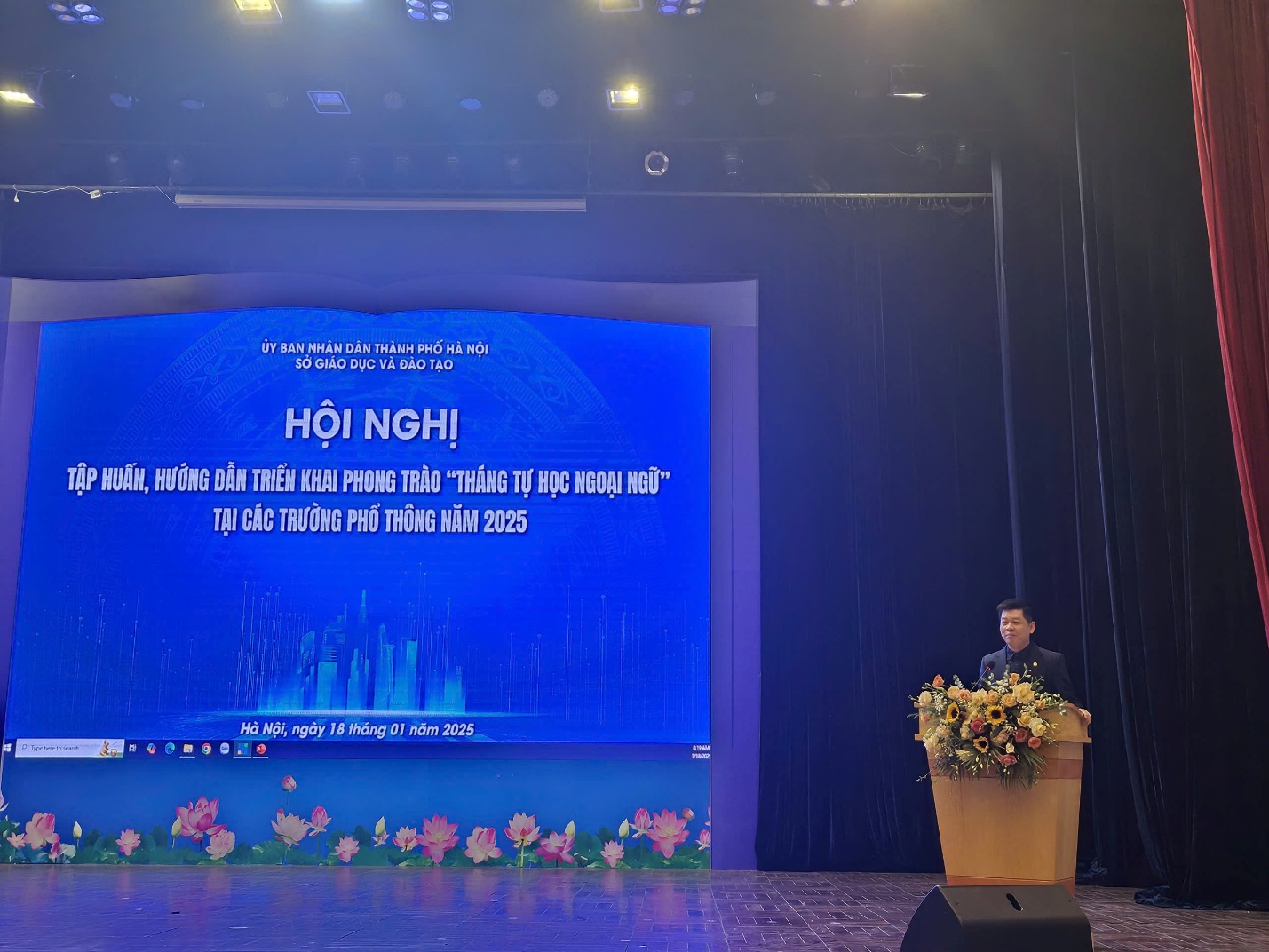 A person standing in front of a podium with flowers

Description automatically generated