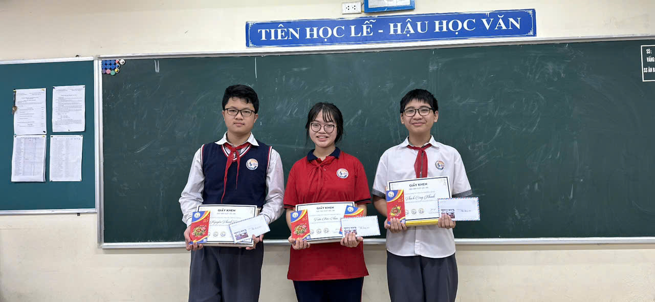 A group of people holding papers in front of a chalkboard

Description automatically generated