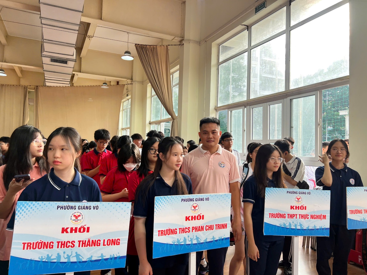 A group of people standing in a room with signs
AI-generated content may be incorrect.