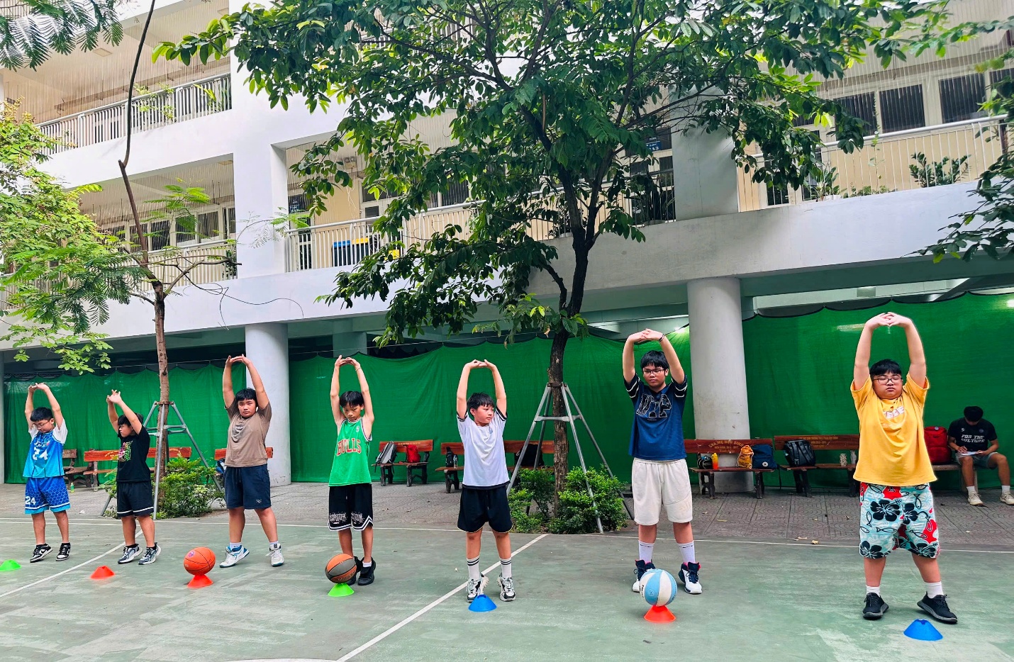 A group of kids standing on a basketball court with their hands upAI-generated content may be incorrect.