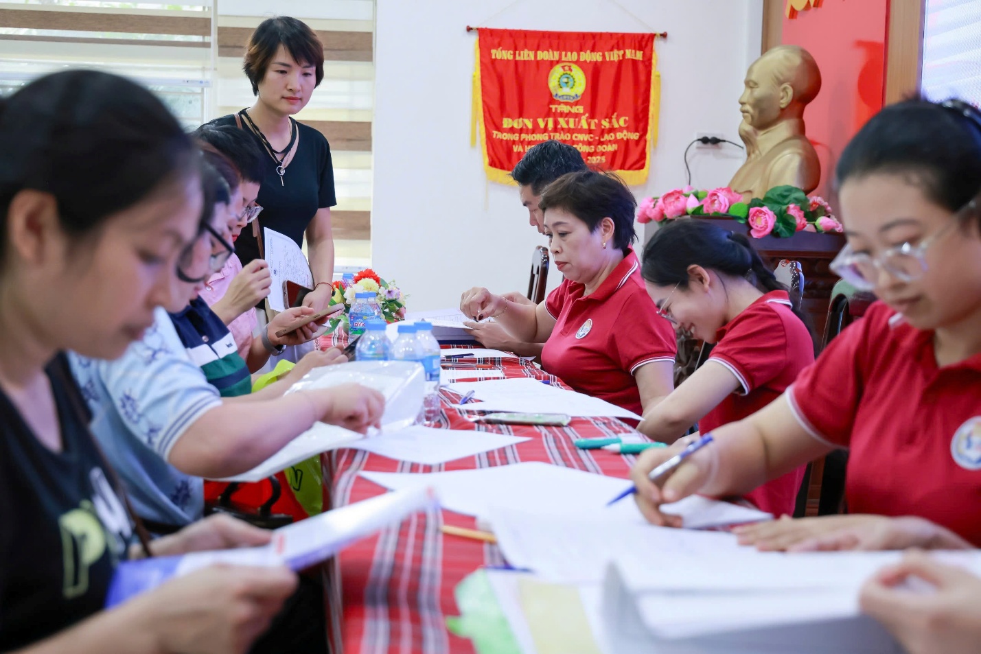 The image shows a group of people, likely in a classroom or workshop, gathered around a table, engaging in some form of collaborative activity, with decorations and a Vietnamese flag in the background.

AI-generated content may be incorrect.