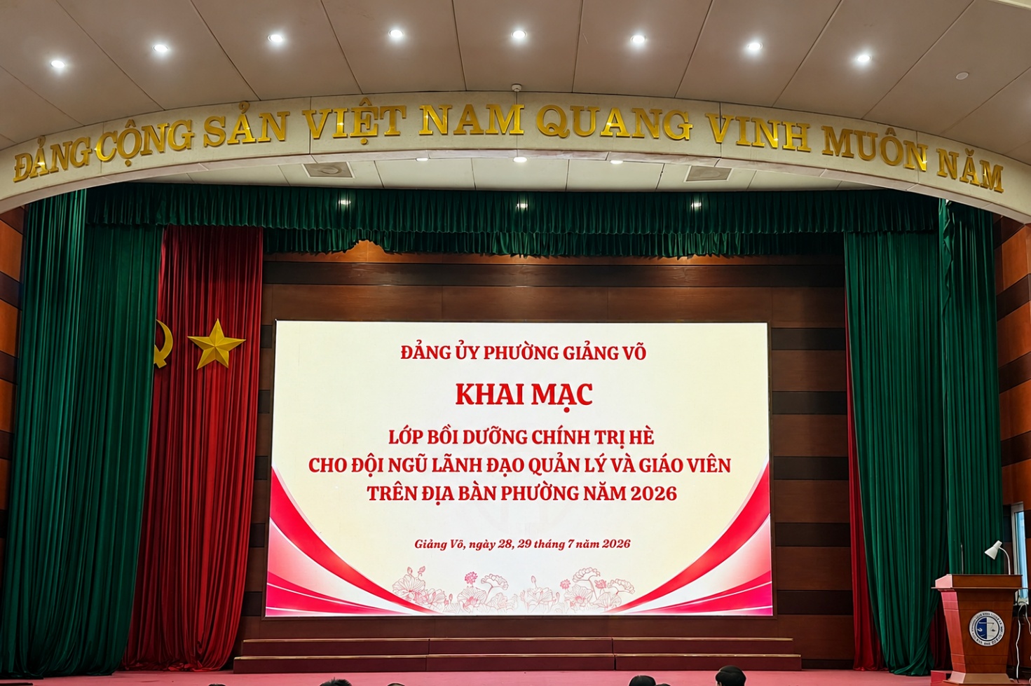 A stage with a screen and red curtains

AI-generated content may be incorrect.